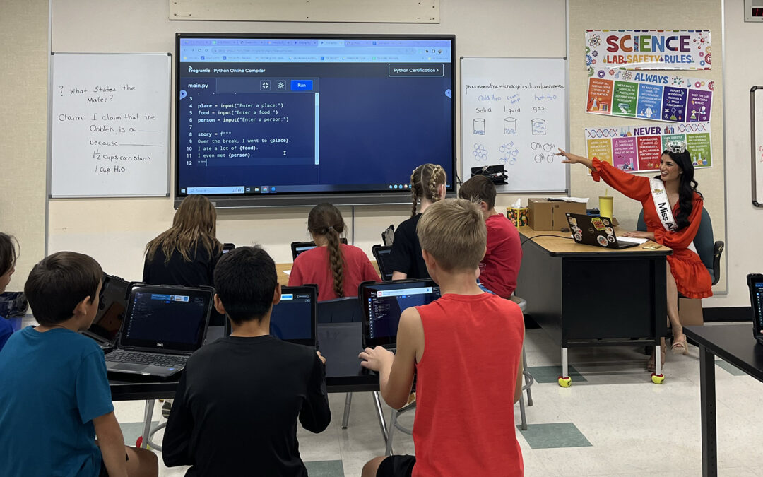 Tiffany Ticlo sits at a desk and gives coding lessons to students.